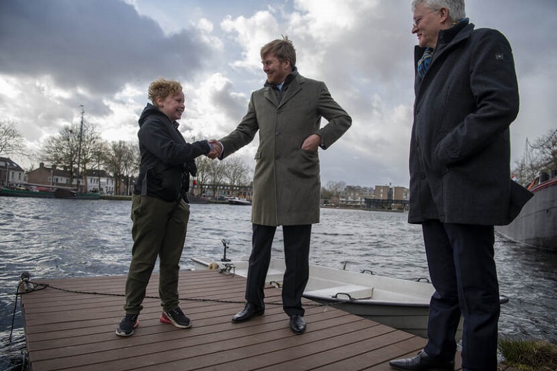 De Koning spreekt met een jonge buurtbewoner die vanuit zijn bootje plastic en ander afval uit de Piushaven haalt. Beeld: ©Gemeente Tilburg / Joris Buijs
